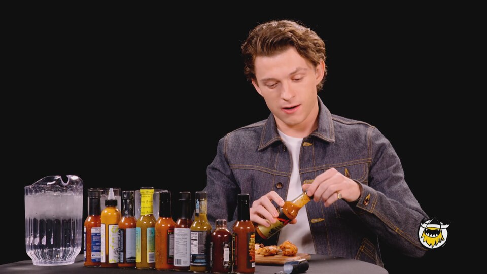 L'acteur Tom Holland essaie des sauces piquantes sur des croquettes de poulet.