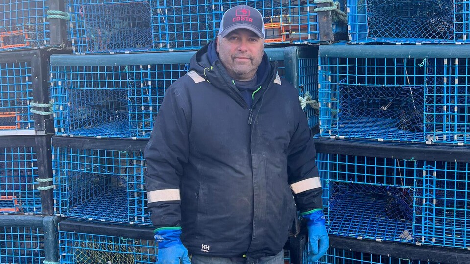 Tommy Amirault devant des casiers bleus de pêche au homard.