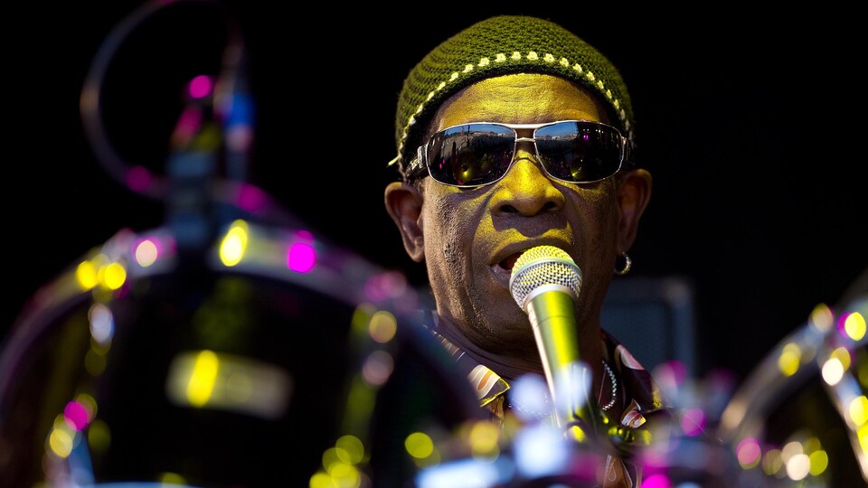 Tony Allen jouant de la batterie tout en chantant au micro.