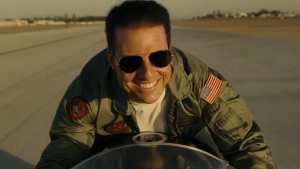 Tom Cruise est sur sa moto et il sourit.