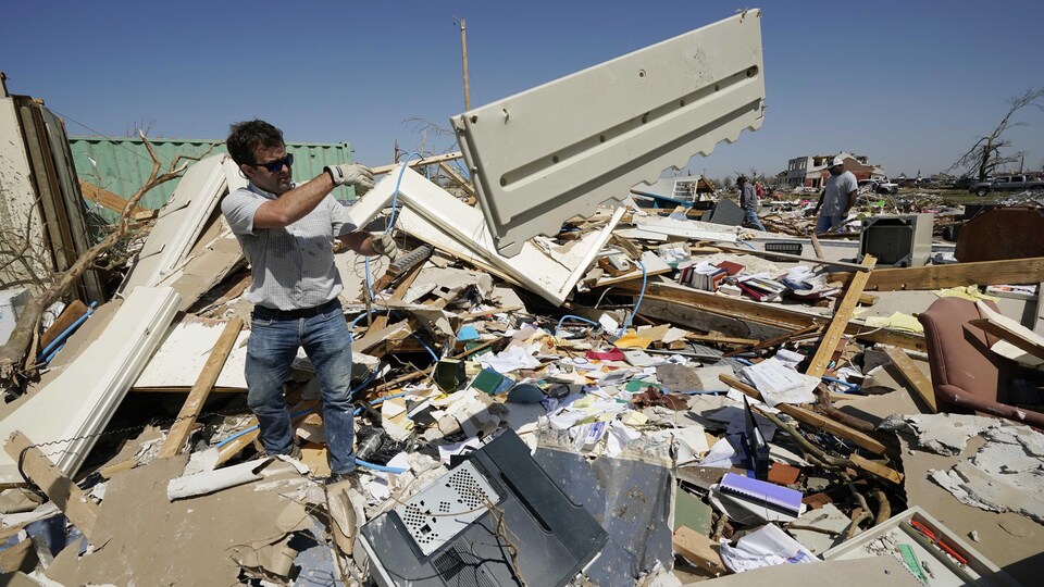 Un homme lance une porte sur une montage de détritus.