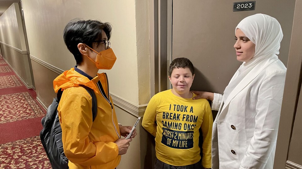 A mother and her two children in the hallway of an apartment building.