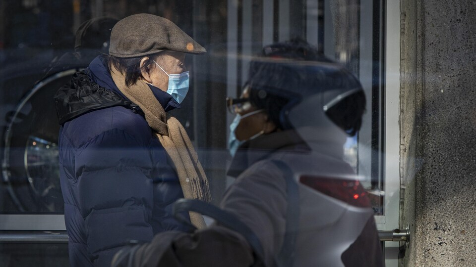 Un homme et une femme portant un masque se croisent dans la rue à Toronto.