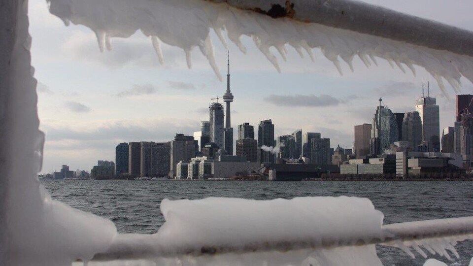 Une rampe glacée au bord du lac Ontario; le centre-ville de Toronto est en arrière-plan.