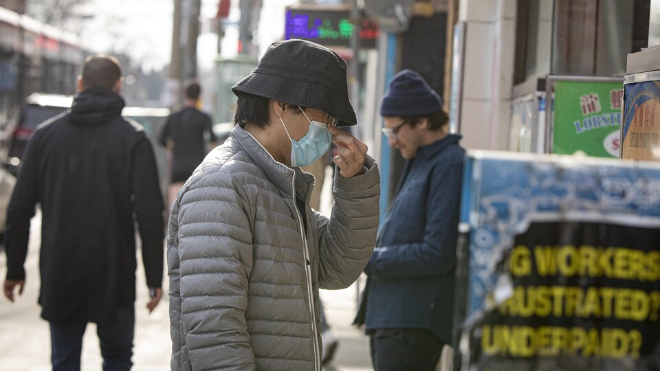 Un homme ajuste son masque dans le quartier chinois de Toronto.