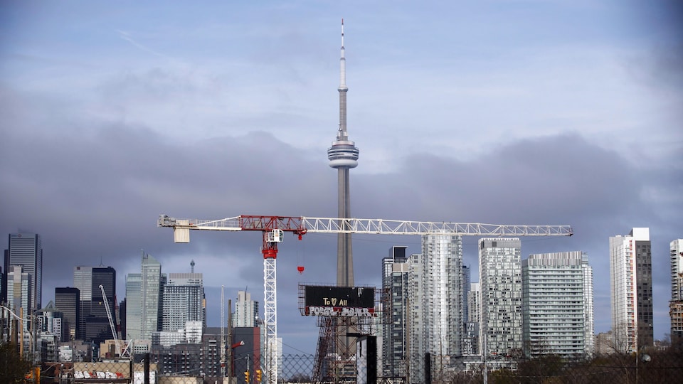 Une grue est visible devant la Tour du CN entourée de tours de condos au centre-ville de Toronto.