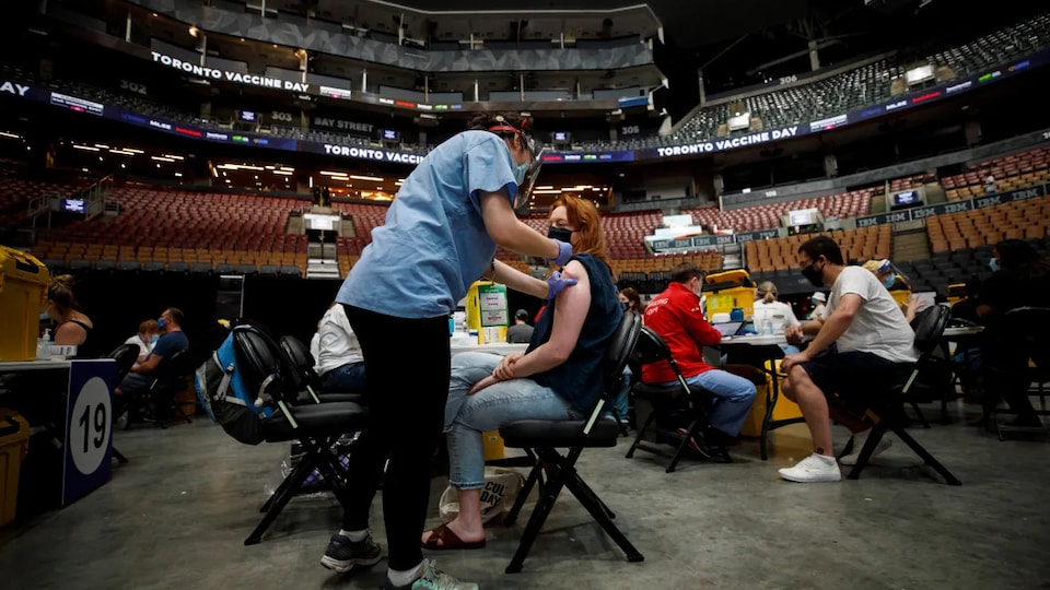 Des gens se font vacciner dans un centre de vaccination de masse.