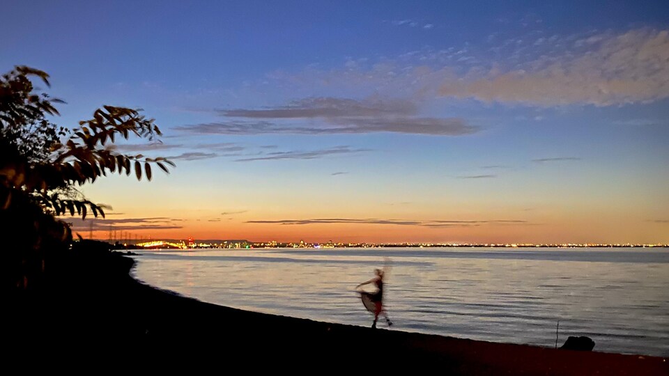 Une femme danse sur une plage de Hamilton devant le coucher de soleil sur le lac Ontario.