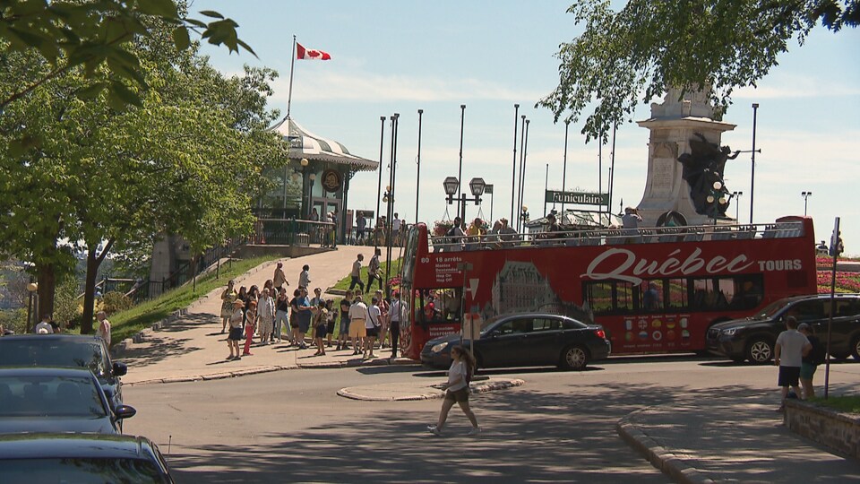 Une rue du Vieux-Québec en bordure de laquelle est stationné un bus touristique rouge.