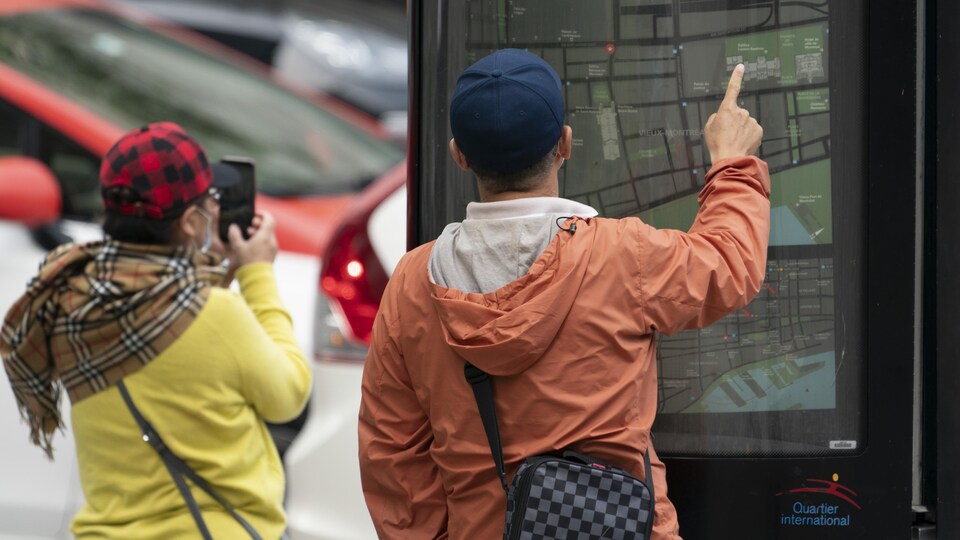 Deux personnes de dos regardent une carte du centre-ville de Montréal.