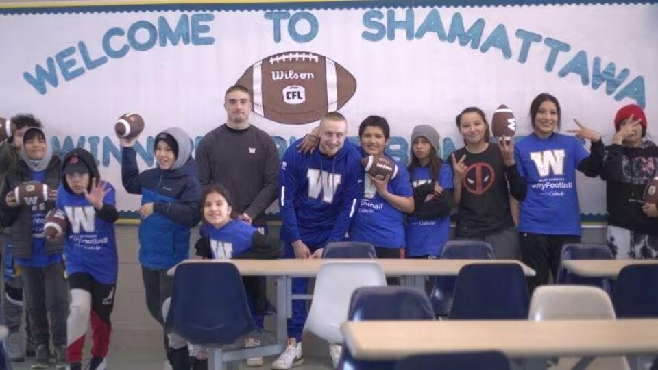 Des joueurs des Blue Bombers entourés par des jeunes.