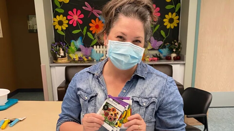 L'infirmière Susan Dyck est assise et tient dans ses mains un petit paquet de graines de tournesols.