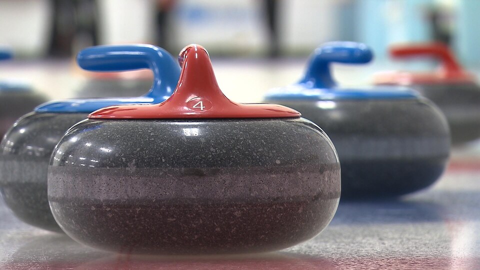 Des pierres de curlings sur la glace.