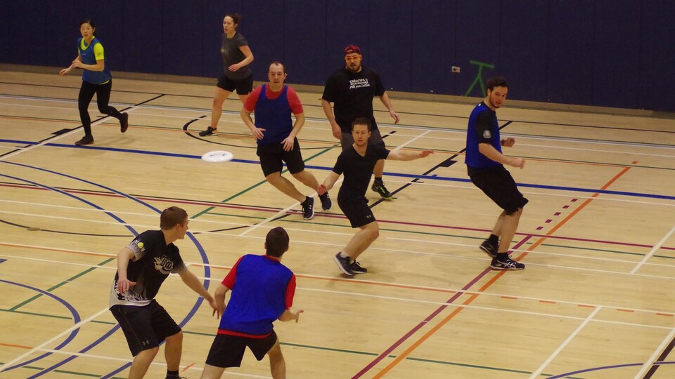 Des joueurs d'utltimate frisbee en action dans un gymnase.