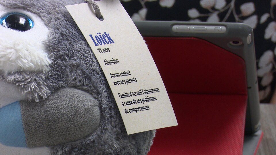 Sur la peluche, une étiquette rapporte que Loïck, 11 ans, a été abandonné et qu'il n'a aucun contact avec ses parents.