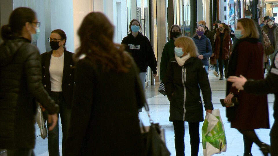 Des clients portent le masque dans l'allée d'un centre commercial.