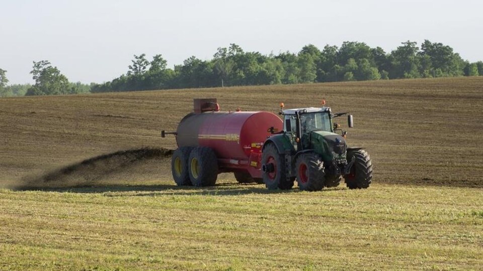 Un tracteur déverse du purin dans un champ.