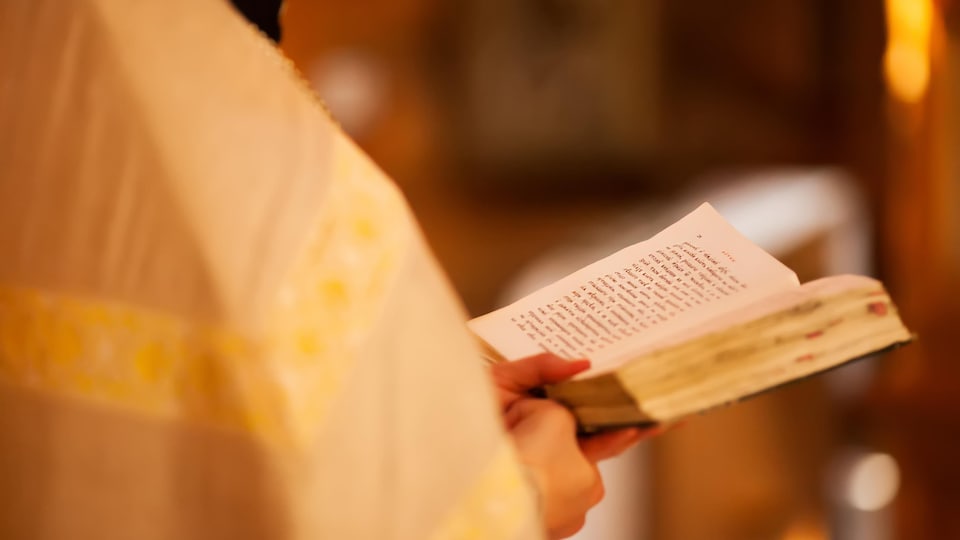 Un membre du clergé tient la Bible dans ses mains.