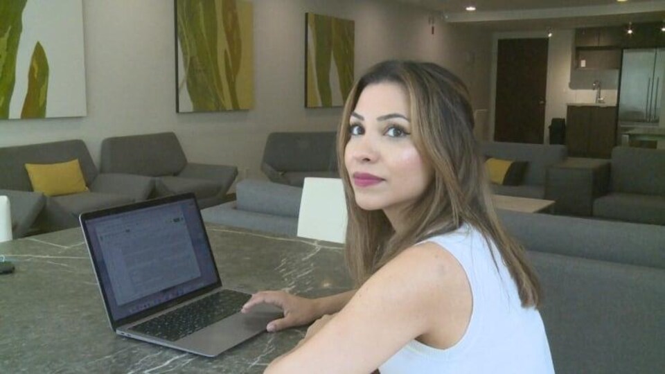 Une femme devant un ordinateur portable, dans un salon.