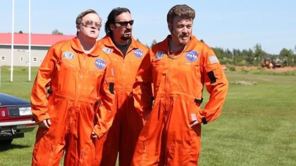 Les trois hommes dans un champs portent une combinaison d'astronaute.