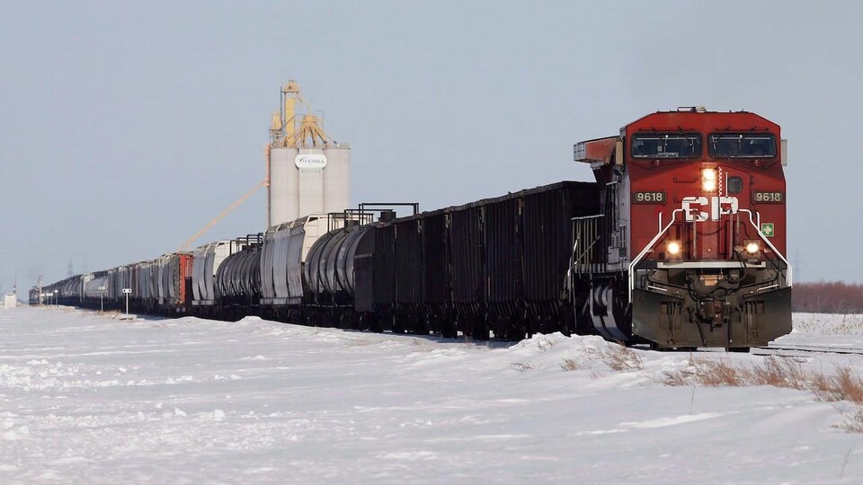 Un train du Canadien Pacifique roule dans un paysage rural en hiver.