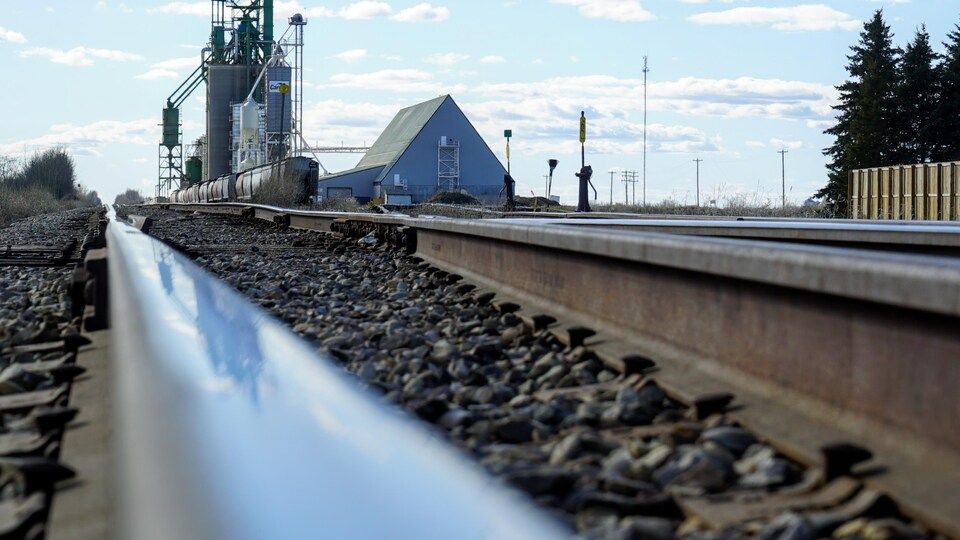 Un chemin de fer devant un silo à grains.