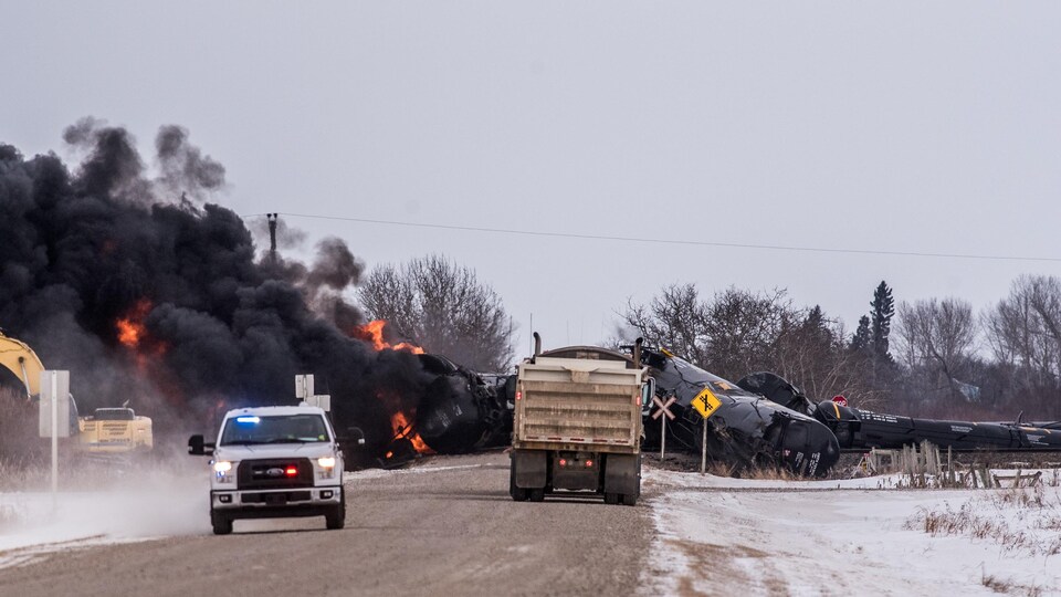 La scène du déraillement, avec de la fumée noire et des camions qui interviennent.