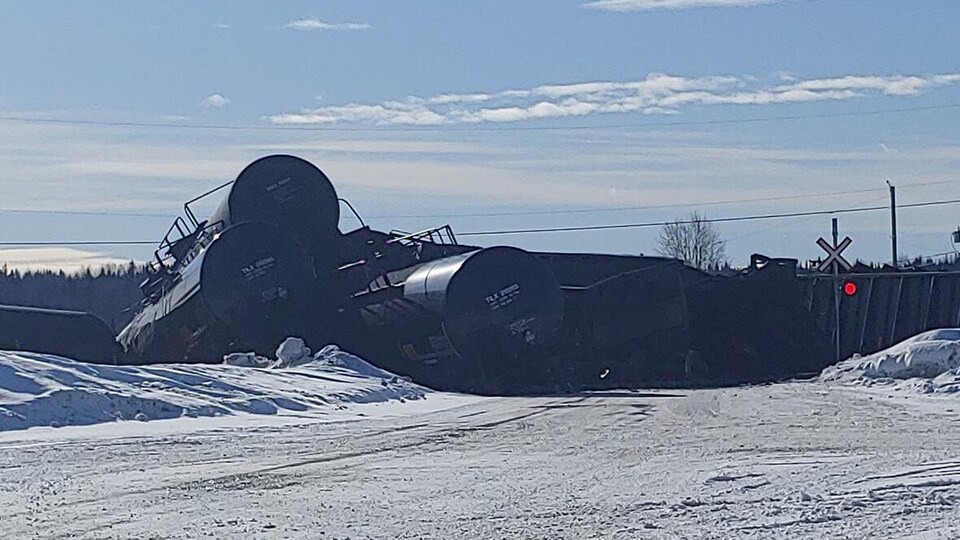 Des wagons de train empilés au bord d'un passage à niveau.