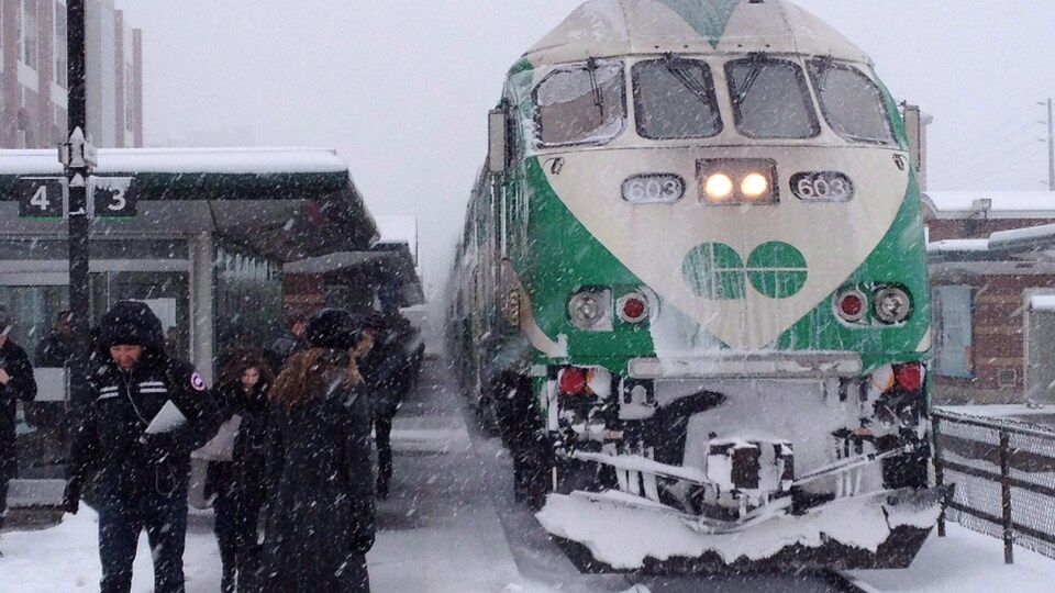 Un train GO, à une gare, sous la neige.