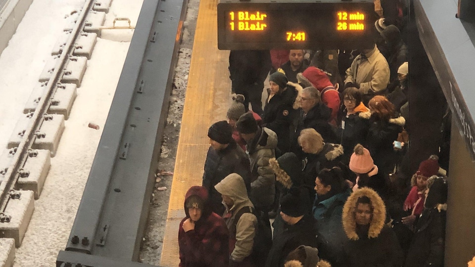 Des dizaines de personnes qui attendent près des rames. 