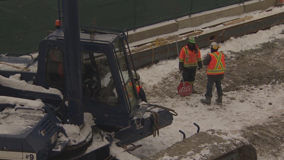 Deux ouvriers près d'un engin sur le chantier de construction