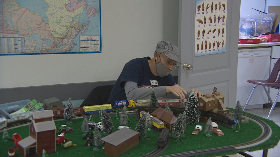 A man sitting in front of a model railroad car. 