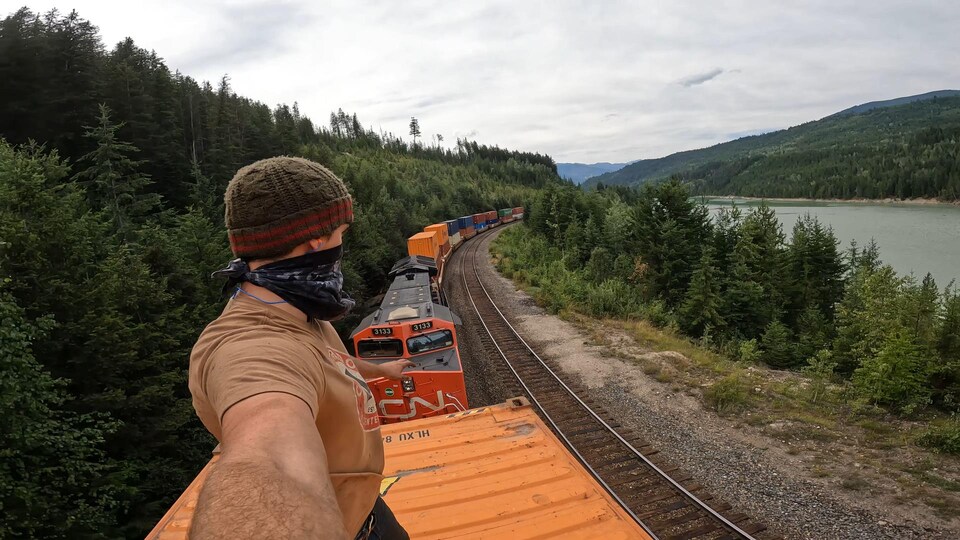 Un jeune homme est debout sur un wagon dans l'Ouest canadien.