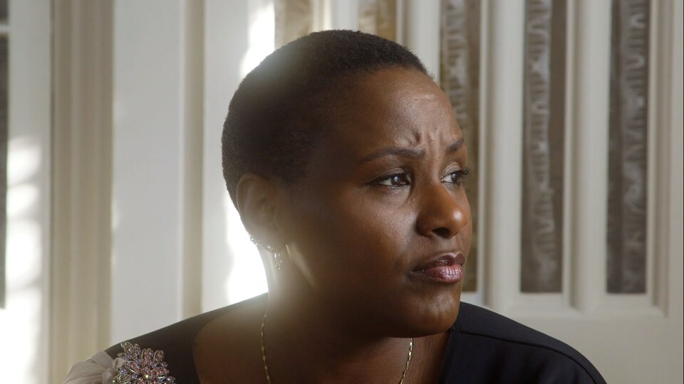 Une femme noire regarde sur le côté.