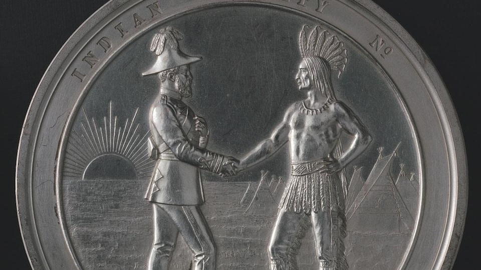 Une médaille sur laquelle sont gravés un chef autochtone et un officier britannique se serrant la main.