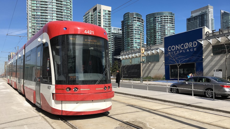 Photo d'un nouveau tramway qui roule sur l'avenue Spadina avec des tours de condos en arrière-plan.