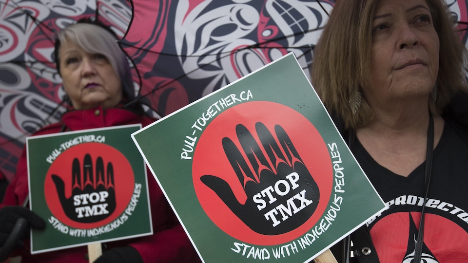 Manifestation contre le pipeline au centre-ville de Vancouver, le 16 décembre 2019 : des femmes portent des pancartes indiquant Stop TMX.