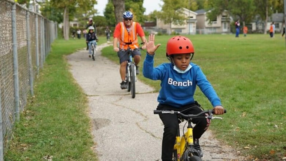 Des élèves à vélo accompagnés d’adultes sur une piste cyclable.