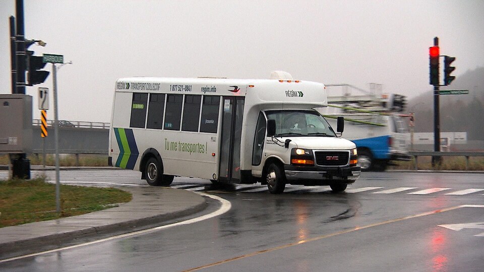 Un véhicule de la Régie intermunicipale de transport Gaspésie—Îles-de-la-Madeleine (RÉGÎM) tourne un coin de rue.