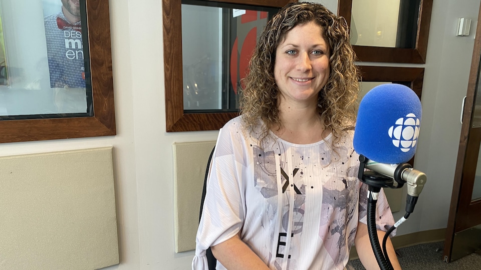 Une personne assise dans le studio de Radio-Canada se tient derrière un micro. 
