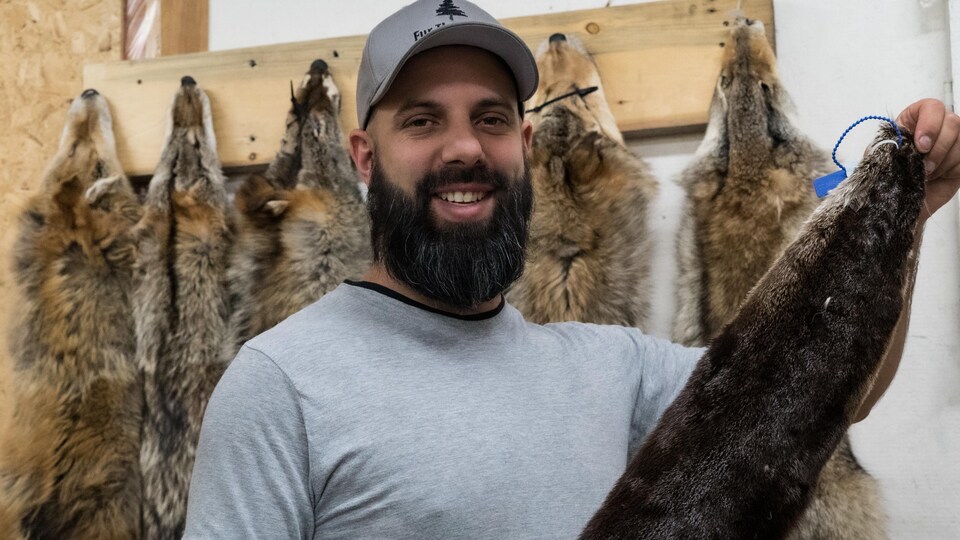 Éric sourit en tenant une peau de loutre.