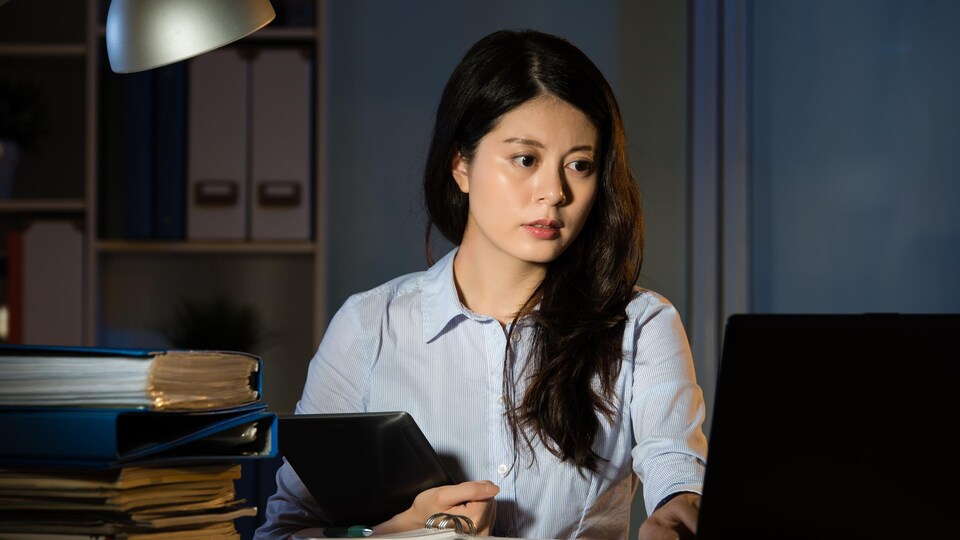 Une femme travail à son bureau la nuit.