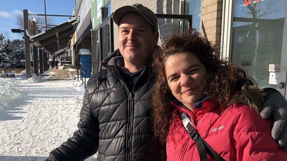 Pascal Pitre et Julie Guay posent pour la caméra sur un trottoir enneigé de Baie-Comeau.