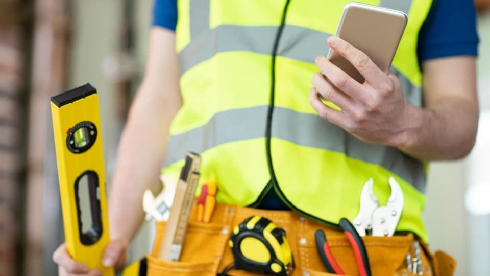 Un travailleur de la construction consulte son téléphone intelligent.