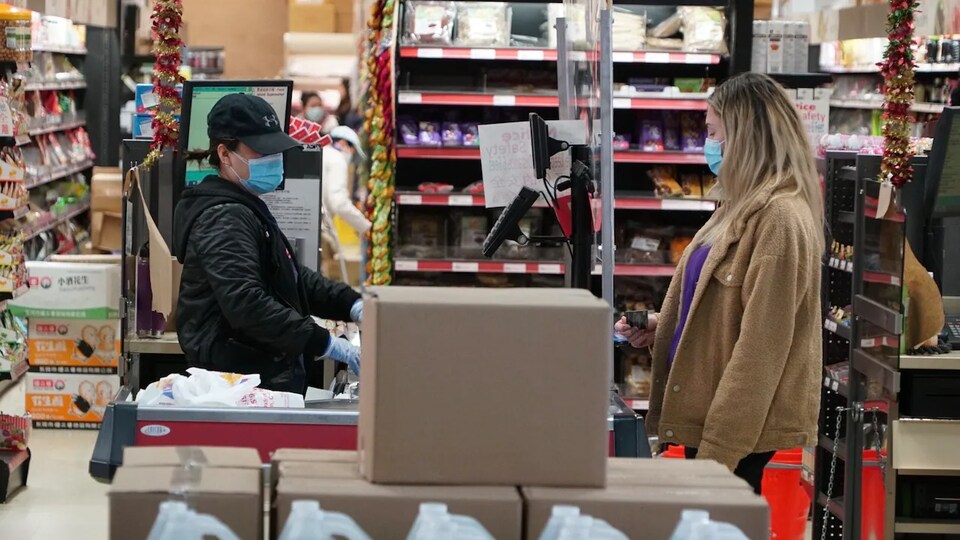 Une caissière dans un magasin d'alimentation s'occupe d'enregistrer les produits d'une cliente.