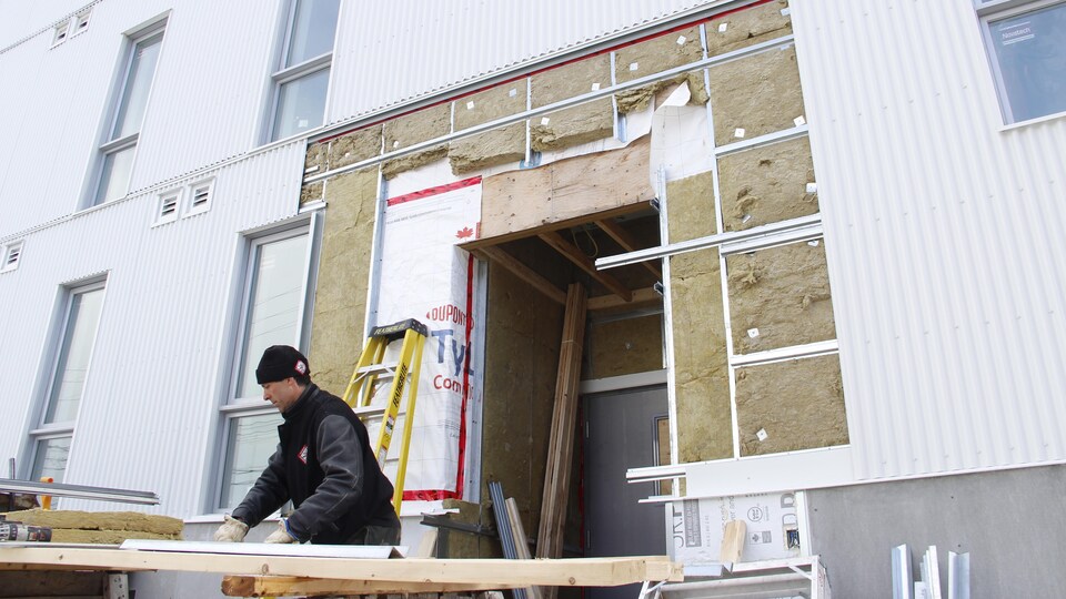 Un homme travaille devant un immeuble.