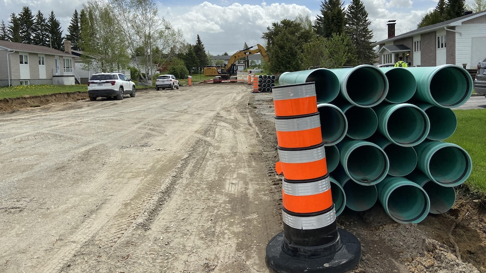 Des tuyaux empilés dans une rue où on a retiré l'asphalte.
