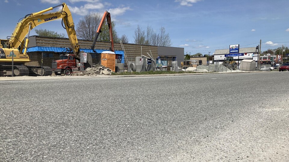 Two cranes in front of a makeshift building. 