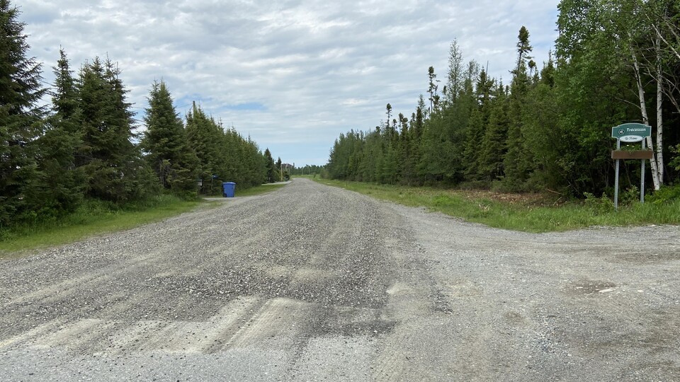 Une route de gravier avec l'affiche Trécesson en bordure.