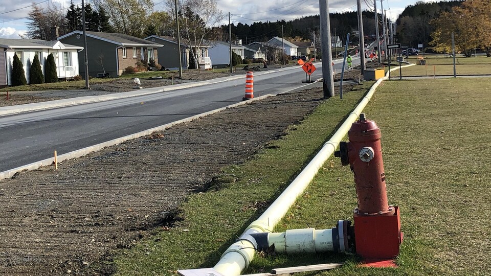 La rue vient d'être asphaltée, des tuyaux qui restent à poser.